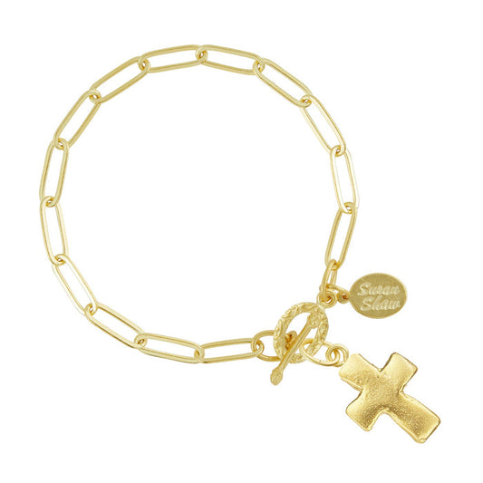 Gold bracelet with a cross charm and tag on a white background