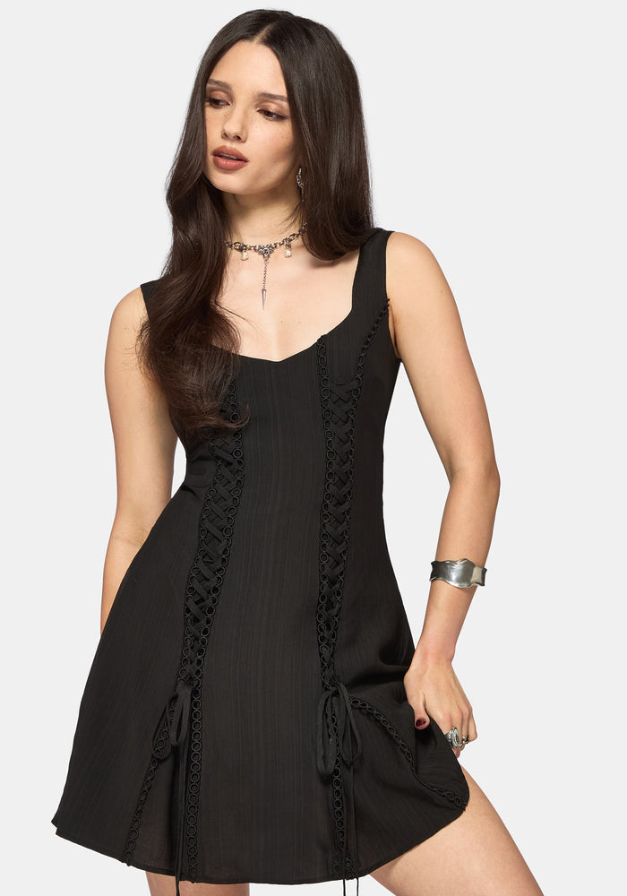 Woman wearing a black mini dress with lace details on a white background