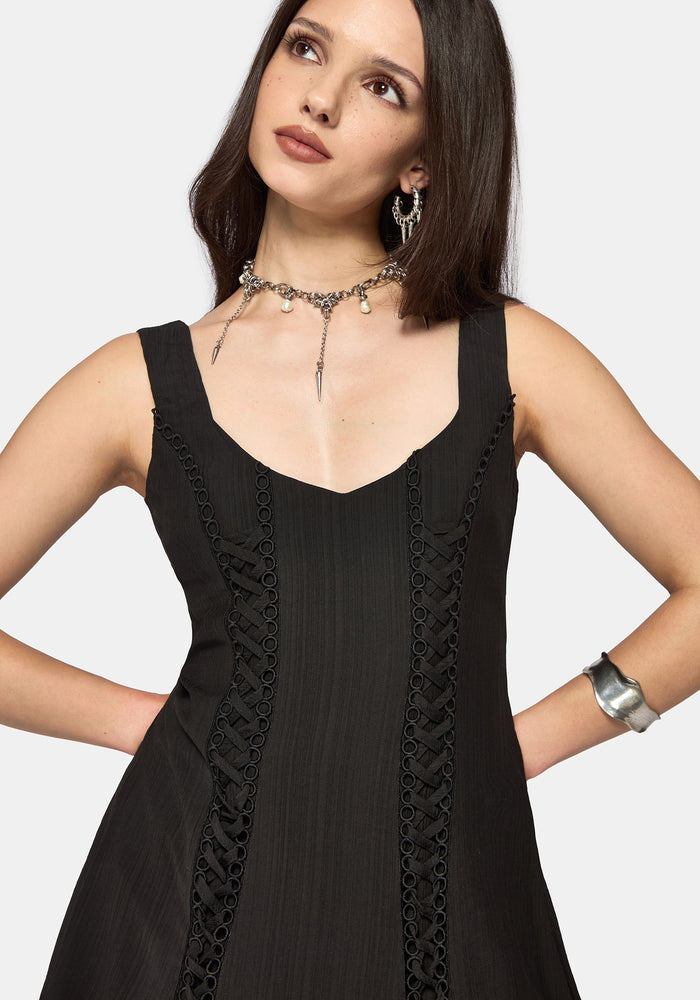 Woman wearing a black mini dress with lace details on a white background