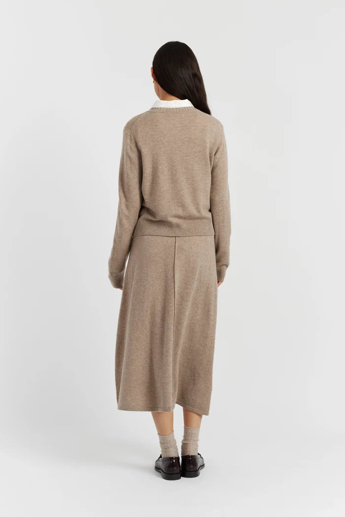 Woman wearing a beige sweater and skirt set on a white background