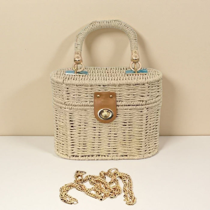 Woven handbag with leather and metal clasp with a chain detail on a beige background
