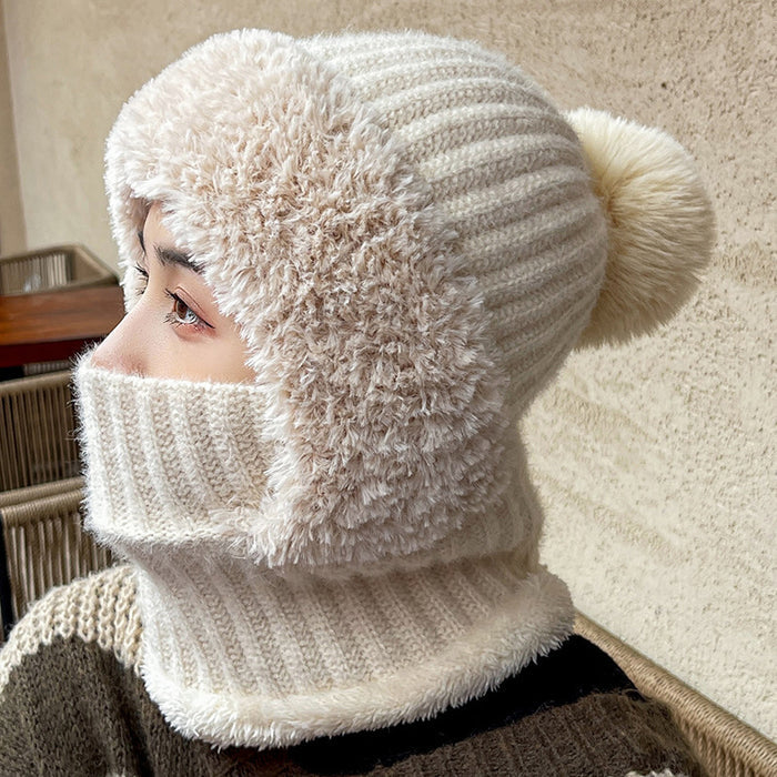 Person wearing a cream-colored knitted hat with a pom-pom and matching scarf.