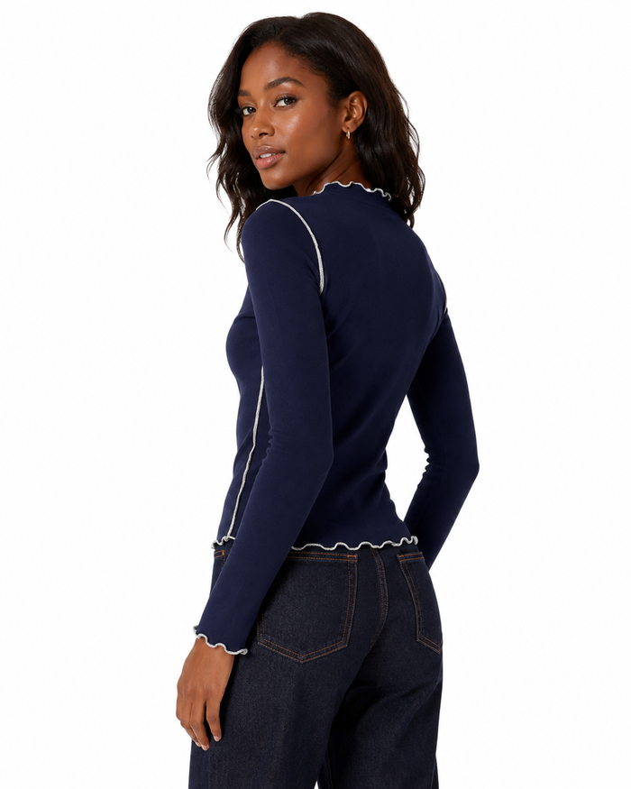 Women's fitted long sleeve top with a mock neckline, lettuce trim edging and visible contrast stitching for everyday styling.